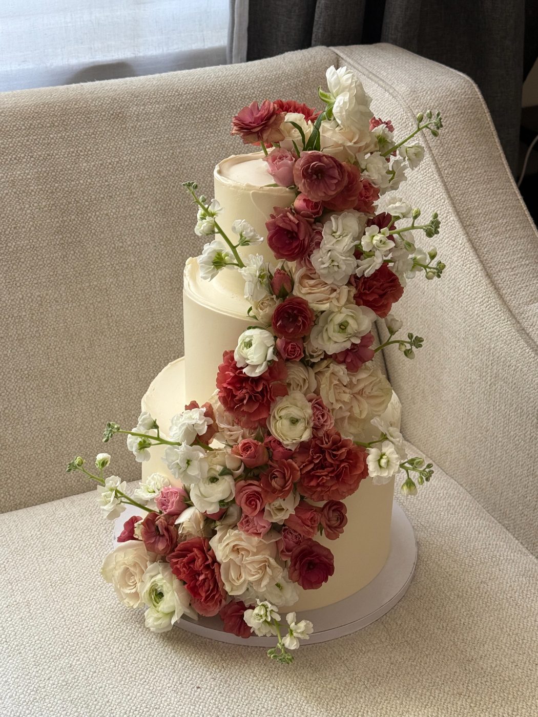 Three-tier cake with cascading roses and ranunculus